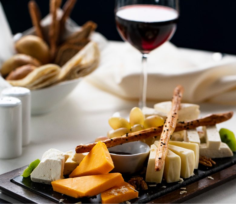 Tabla de quesos y picos con una copa de vino tinto