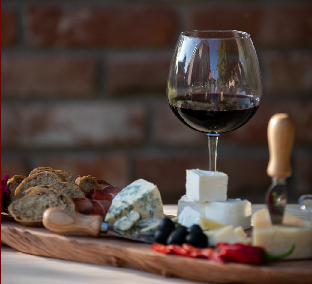 Tabla de quesos y embutidos con una copa de vino tinto